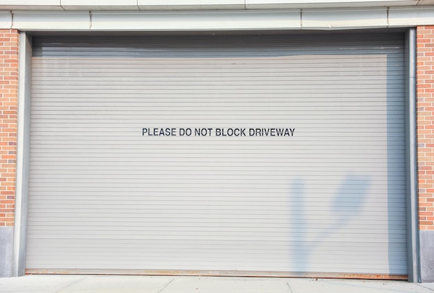 Een garagedeur met een bord waarop staat: "Blokkeer weg".