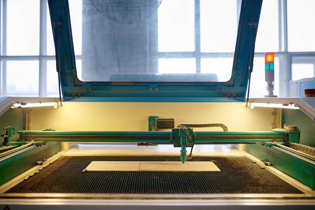 Een geautomatiseerde CNC-lasermachine die werkt met een houten plank. Houtbewerking, snij- en graveerproces