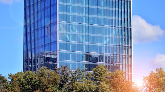 een gebouw met een blauwe glazen gevel en bomen op de achtergrond