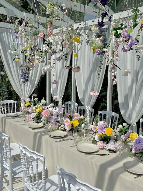 Een gedekte tafel voor een bruiloft met bloemen die aan het plafond hangen.