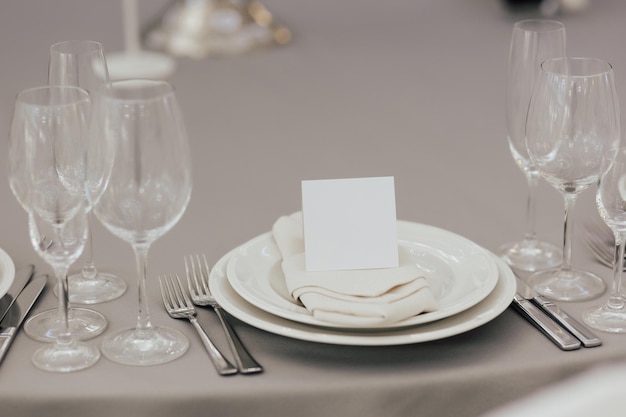 Een gedekte tafel voor een diner met een glazen bord en een witte kaart erop