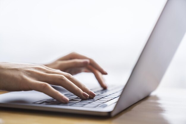 Foto een gedetailleerde opname van de handen van een vrouw die typt op een geavanceerd laptoptoetsenbord tegen een wazige kantooromgeving