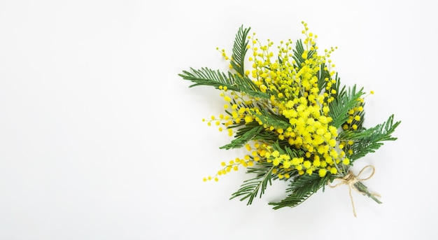 Een geel boeket mimosa en een geschenkdoos en een kraftpapieren zak wenskaart voor international womens day spring festival 8 maart pasen kopieer ruimte