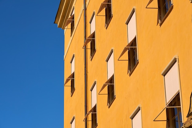 Een geel gebouw met meerdere verdiepingen met een blauwe lucht op de achtergrond