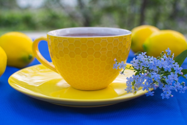 Foto een geel porseleinen kopje thee met een gele schotel op een tafel met een blauw tafelkleed en delicate blauwe bloemen