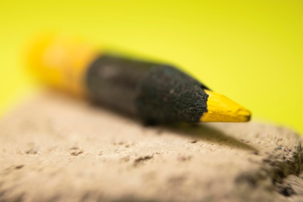 Een geel potlood met een zwarte punt die een zwarte punt heeft.