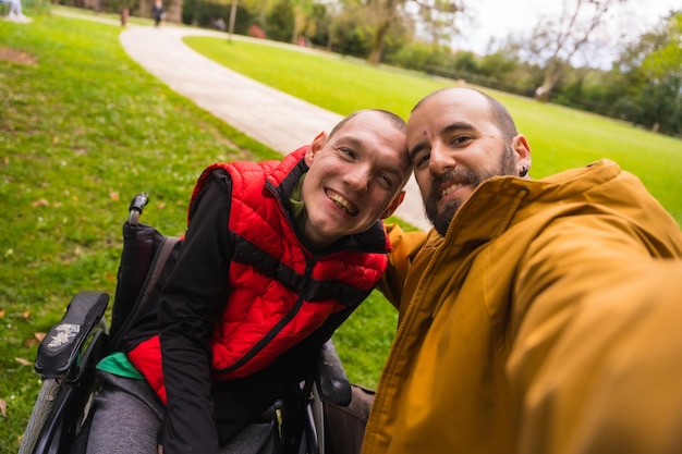 Een gehandicapte in een openbaar stadspark in de rolstoel selfie met een vriend in het park