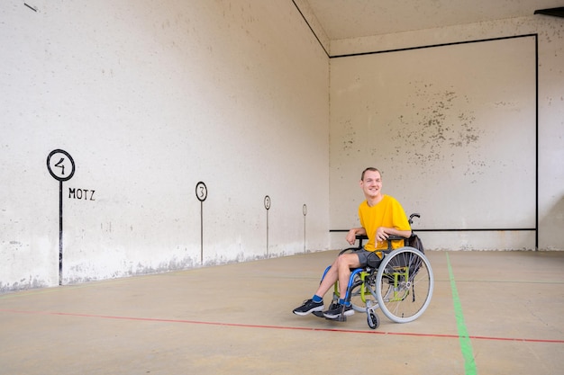 Een gehandicapte in een rolstoel bij een Baskisch pelotaspel fronton glimlachend