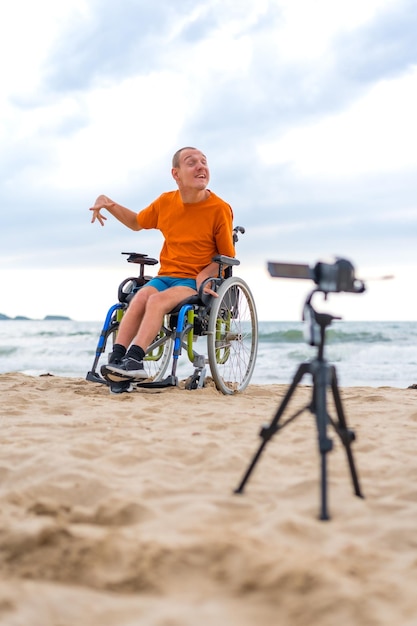 Een gehandicapte persoon in een rolstoel die een video opneemt naast het strand