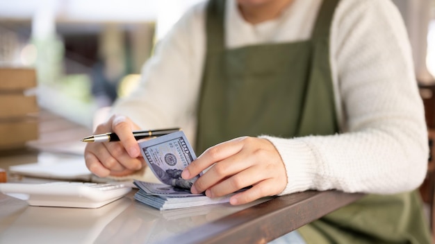 Foto een gekapte foto van een vrouwelijke eigenaar van een klein bedrijf die haar winkelbudget beheert en contant geld telt