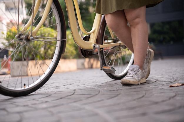 Foto een geknipte opname van de benen van een vrouw die een fiets op straat in de stad loopt en duwt