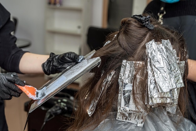 Een gekwalificeerde master-colorist verft het haar van een vaste klant in een schoonheidssalon Concept van haarkleuring voor staande klanten