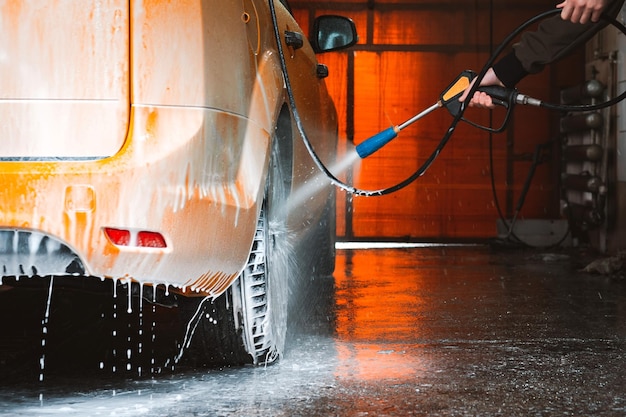 Een gele auto wassen bij een contactloze selfservice carwash Een sedan auto wassen met schuim en water onder hoge druk