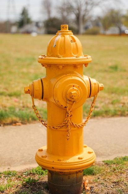 Een gele brandkraan staat op een stoep voor een gebouw.