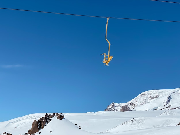 Een gele stoel van een skilift in de bergen op een blauwe achtergrond