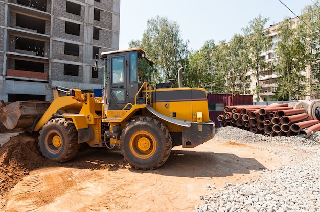 Een gele tractor op een bouwplaats egaliseert de grond