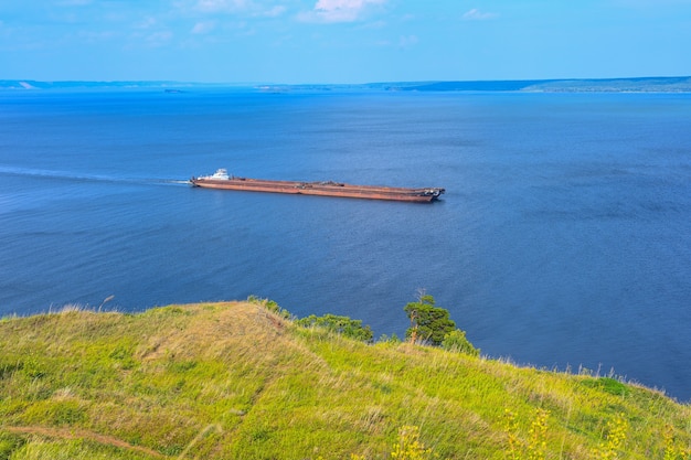 Een gelede sleepboot en barge bulkcarrier vervoert zand en bouwmaterialen op de rivier. de grote schuit vaart langs de brede wolga. transport industrie.