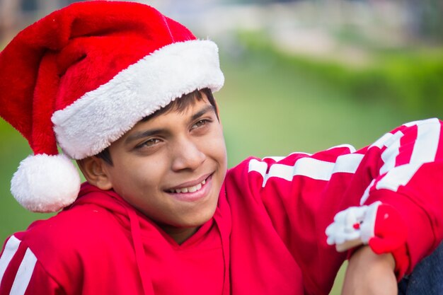 Een gelukkig, aantrekkelijk lachend kind in kerstmuts, vrolijk op afstand kijkend