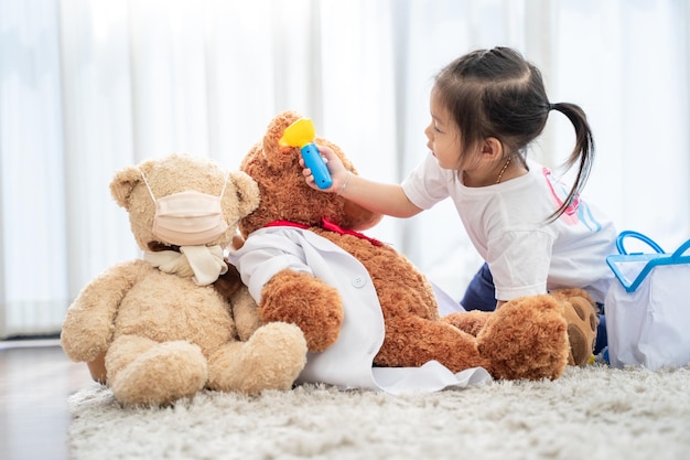Een gelukkig Aziatisch meisje dat dokter of verpleegster speelt en een stethoscoop luistert naar speelgoed