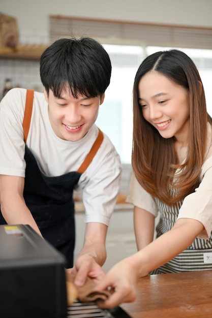 Een gelukkig Aziatisch stel dat dienblad in de oven zet, geniet van samen bakken in de keuken