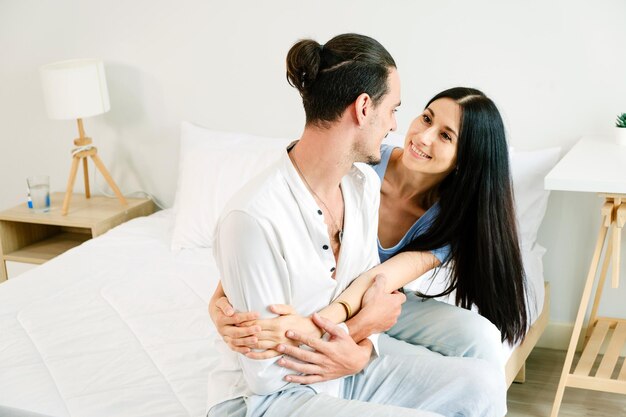 Foto een gelukkig blank echtpaar zit op een comfortabel bed, ontspant en kijkt elkaar in de ogen.
