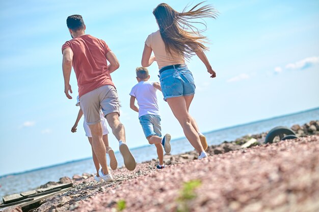 Een gelukkig gezin dat zich opgewonden voelt en op een strand rent