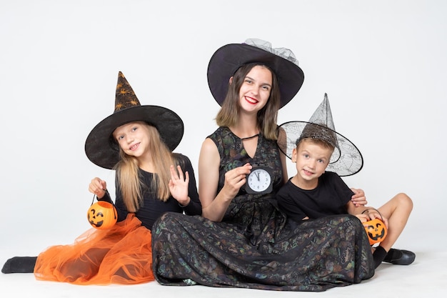Een gelukkig gezin, een moeder en kinderen in griezelige heksen- en tovenaarskostuums met zwarte horloges en manden met lekkernijen