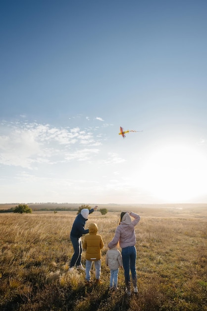 Een gelukkig gezin met kinderen lanceert een vlieger en brengt samen tijd door in de frisse lucht. Fijne kinder- en familievakanties.