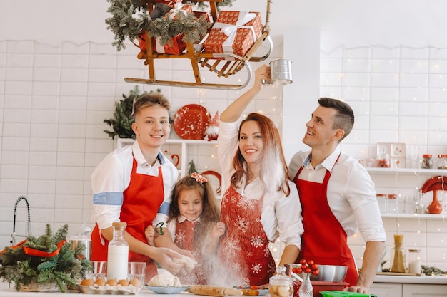 Een gelukkig gezin staat in de kerstkeuken en bereidt deeg voor het maken van koekjes