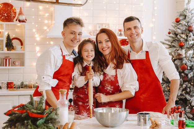 Een gelukkig gezin staat in de kerstkeuken en bereidt deeg voor het maken van koekjes