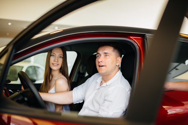 Een gelukkig jong stel kiest en koopt een nieuwe auto bij een autodealer. Een nieuwe auto kopen.