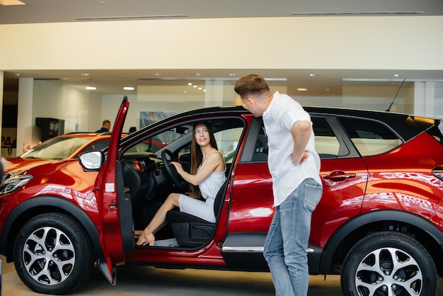 Een gelukkig jong stel kiest en koopt een nieuwe auto bij een autodealer