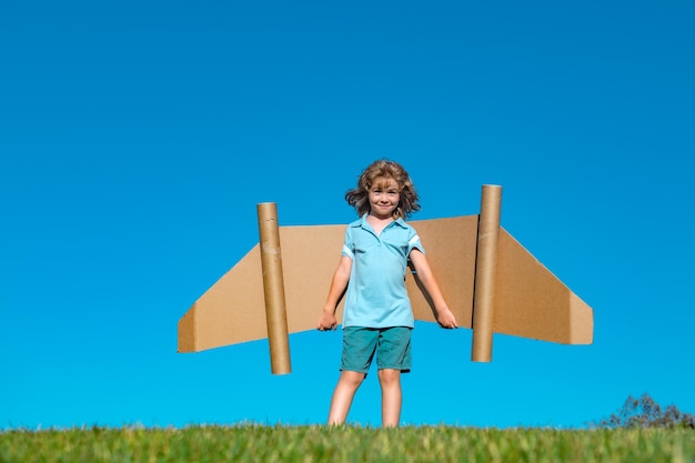 Een gelukkig kind dat buiten speelt op groen gras en een blauwe hemel, een piloot met een jetpack, een jongen die met speelgoed speelt