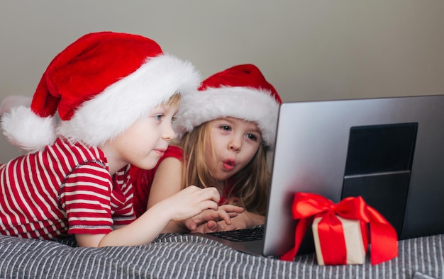 Een gelukkig meisje en een jongen kijken naar een laptopscherm, virtuele communicatie, gefeliciteerd. Het concept van nieuwjaarsvakantie en kinderen, virtuele communicatie