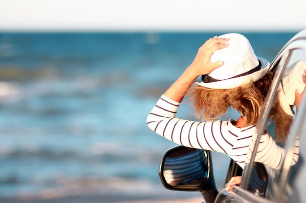 Een gelukkig meisje in de auto aan zee in de natuur op vakantiereizen