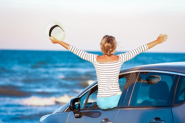 Een gelukkig meisje in de auto bij de zee in de natuur op vakantie reizen