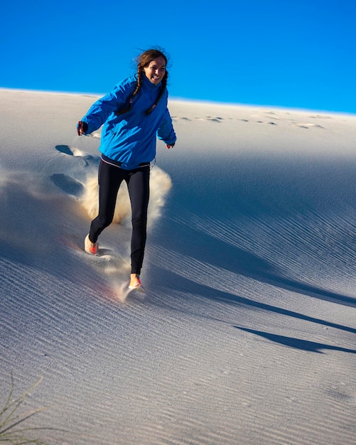 Een gelukkig meisje rent vanaf de top van een enorme zandduin in Coral Bay, West-Australië