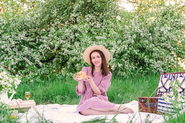 Een gelukkig mooi meisje op een romantische picknick in de natuur houdt een schaaltje croissants in haar handen