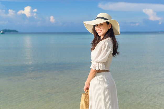 Een gelukkig mooie vrouw in witte jurk genieten en ontspannen op het strand, zomer en vakantie concept