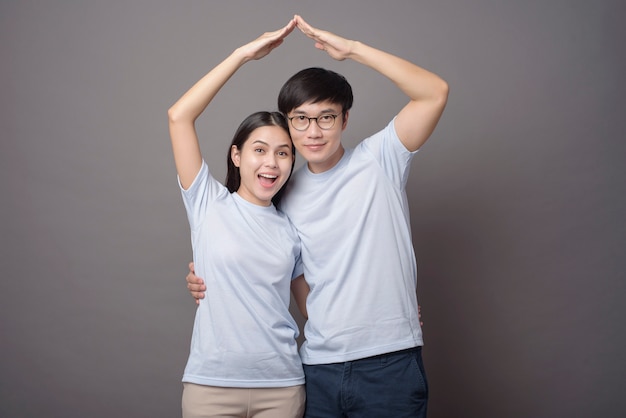 Een gelukkig paar dat blauw overhemd draagt, maakt in grijs een armsroof