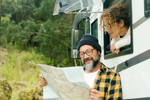 Een gelukkig reizigerspaar dat samen een papieren gidskaart bekijkt om het plan voor de volgende reisbestemming te kiezen Wonen in een busje Nomadische mensen Vanlife Alternatieve voertuigvakantiereis Roadtripplanning