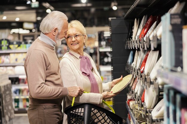 Een gelukkig seniorenpaar koopt keukengerei in de supermarkt