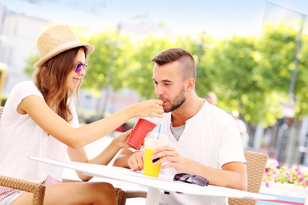 een gelukkig stel dat smoothies drinkt in een buitencafé