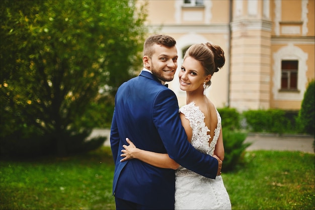 Een gelukkig stel jonggehuwden knuffelen na de huwelijksceremonie buiten, mooi modelmeisje