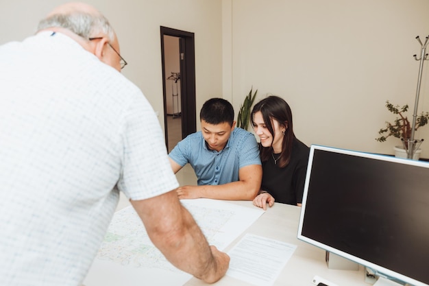 Een gelukkig stel tekent samen een contract op kantoor een man en een vrouw kopen een appartement en ondertekenen een contract