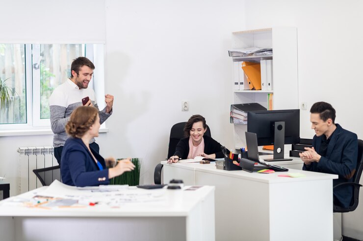 Een gelukkig team, dat zojuist geweldig nieuws via de telefoon heeft ontvangen, juichend op kantoor