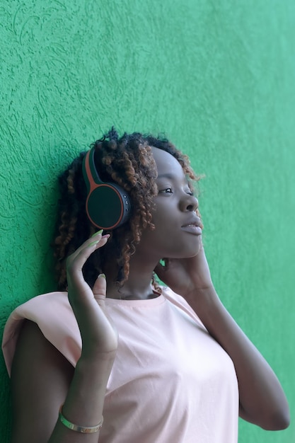 Een gelukkige Afro-Amerikaanse vrouw luistert naar muziek met een koptelefoon Entertainment en recreatie