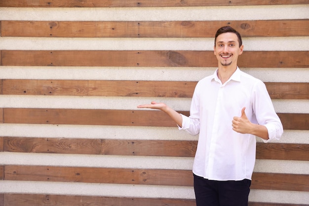 Een gelukkige blanke man met een baard in een wit overhemd en een zwarte broek met iets in zijn handpalm