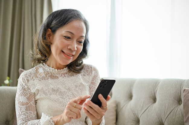 Een gelukkige en lachende Aziatische vrouw gebruikt haar smartphone om te sms'en met haar vrienden