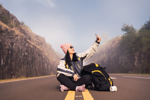 Een gelukkige en lachende reiziger neemt een selfie midden op de weg.